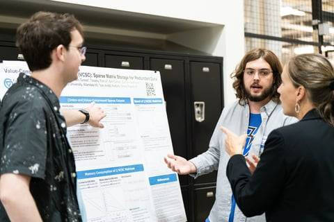 A group of students talking in front of a research poster.